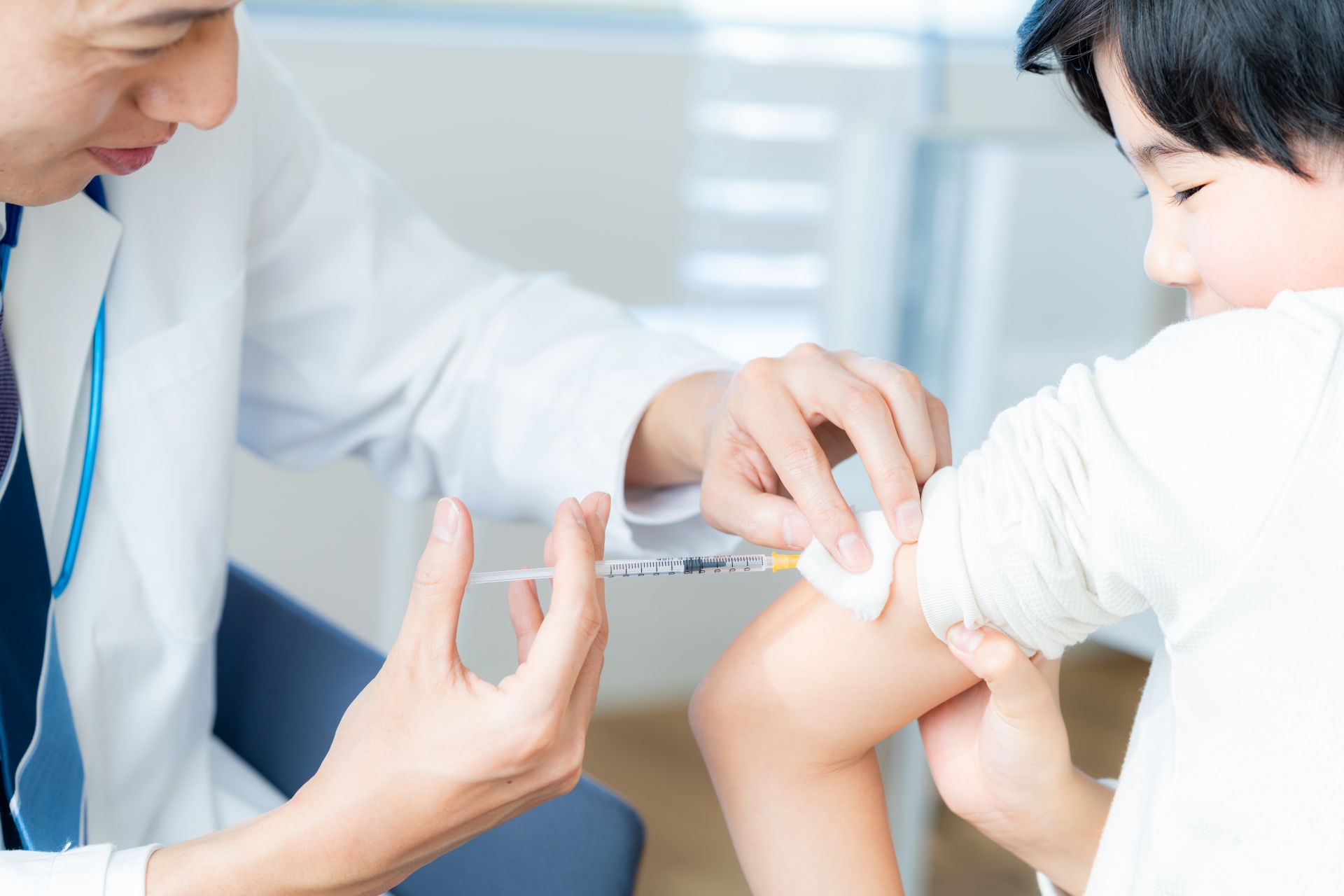 Doctor giving a child a vaccination with a syringe in the upper arm